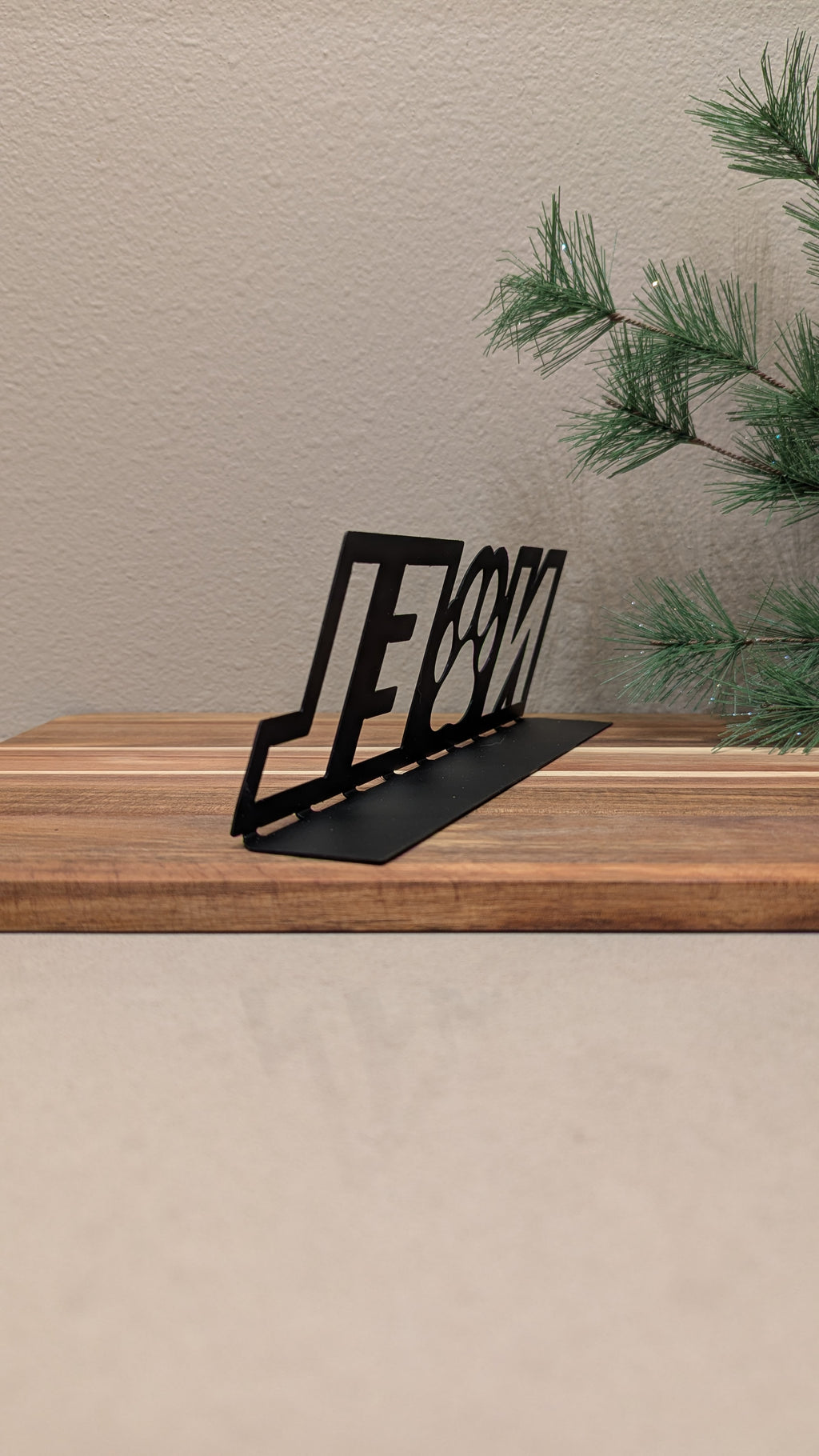 Rear quarter profile Image of a  black metal sign with the word "NOEL" and a paw for the "o" from Atomic Rat Rods & Metal Werks.