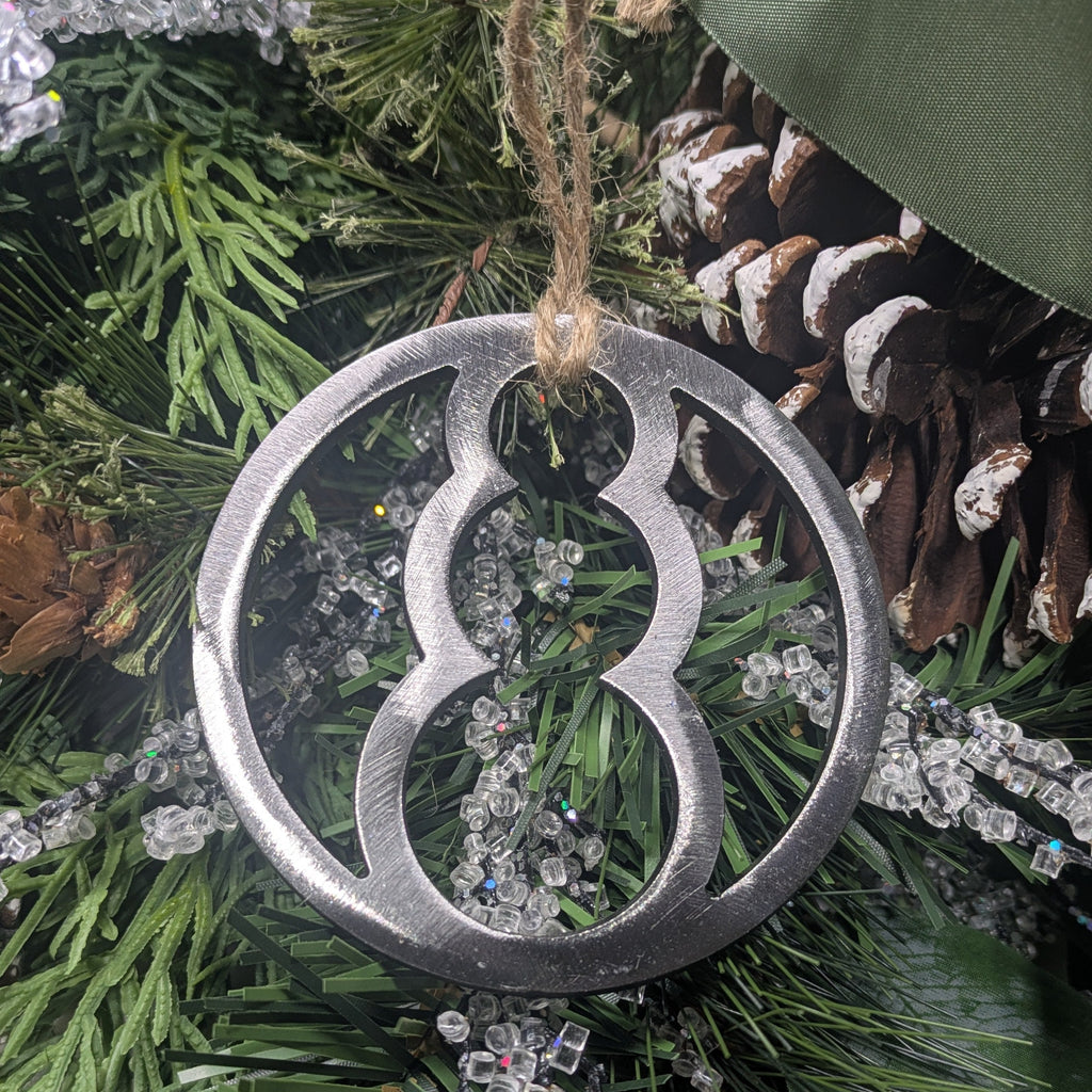 Image of a simple, minimalist silver-colored snowman ornament on a Christmas tree from Atomic Rat Rods & Metal Werks.