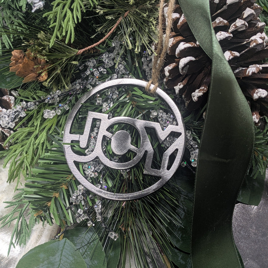 Decorative ornament with 'JOY' on a green leafy background
