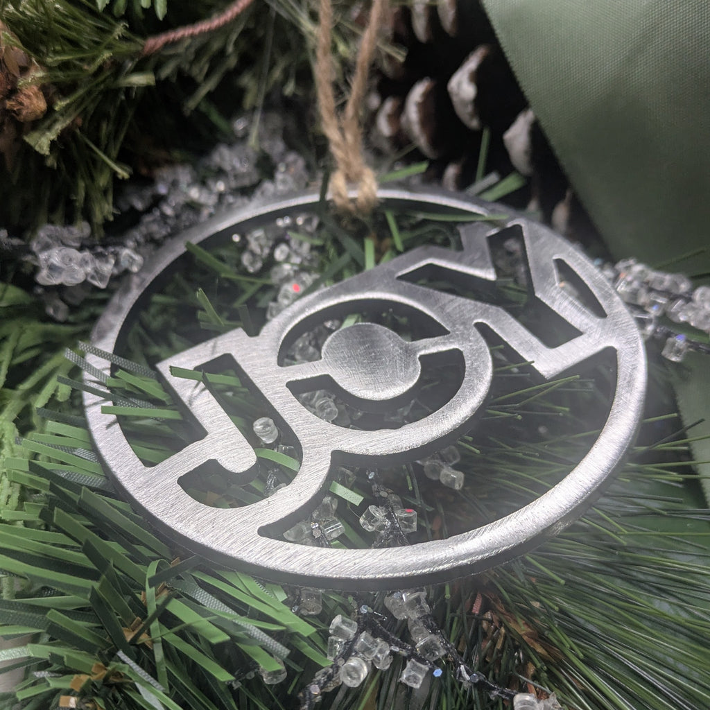 Lower angle image of a simple, minimalist silver-colored "HOPE" ornament on a Christmas tree from Atomic Rat Rods & Metal Werks.